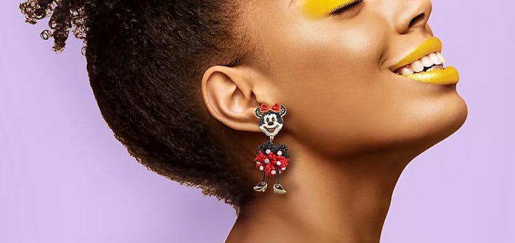 A happy woman wears Minnie Mouse Disney Parks x BaubleBar earrings.