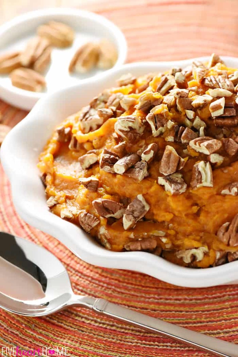 Sweet potato casserole in white bowl placed on top of colorful place mat with a spoon next to it