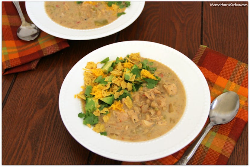 white bean chicken chili with tortilla chips and avocado garnishes served in white bowl on wood tabl...