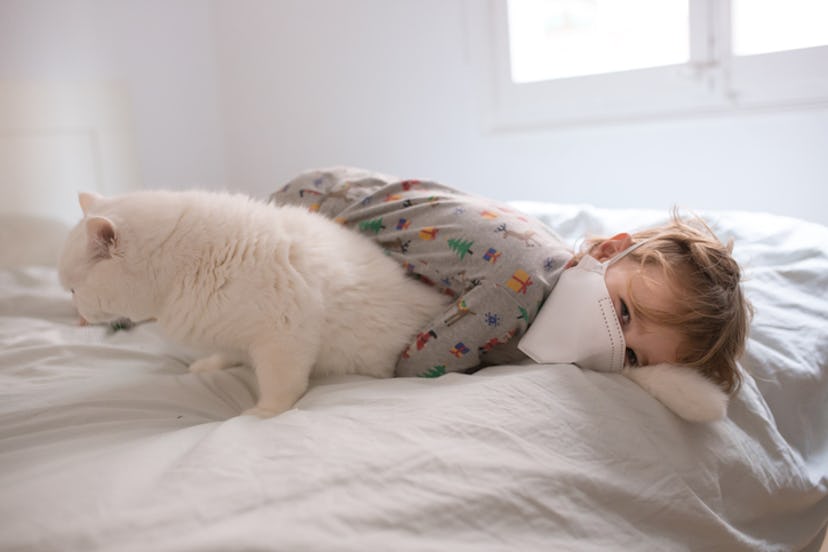 Boy in mask cuddling with cat