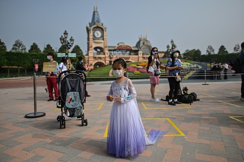 young girl wearing mask and princess dress at theme park