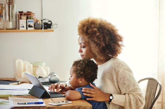 A mother working on laptop with child on lap