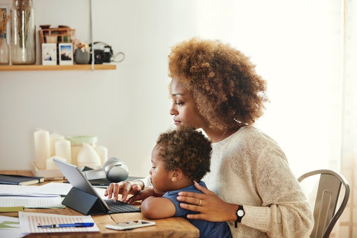 A mother working on laptop with child on lap