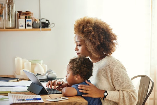 A mother working on laptop with child on lap