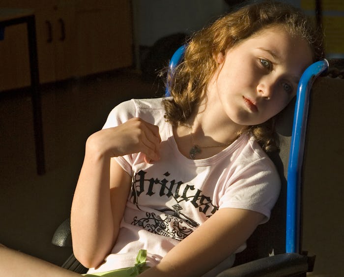 A girl sits in wheelchair with sunlight lighting up her face