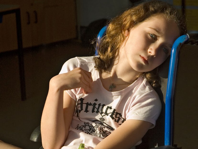 A girl sits in wheelchair with sunlight lighting up her face