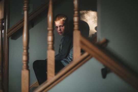 An LGBTQIA+ kid on the stairs of a foster home