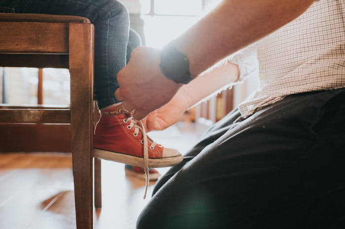 A closeup of a parent tying their kid's Converse comfy sneakers