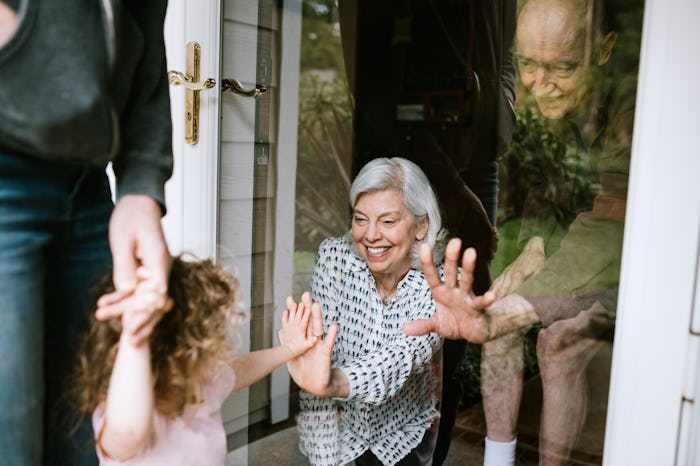 young girl giving grandparents high five through window