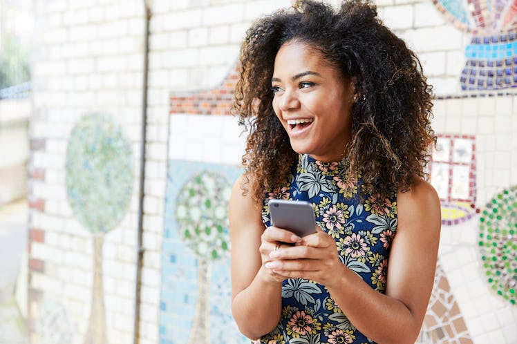 Woman with smart phone next to tiled mosaic wall