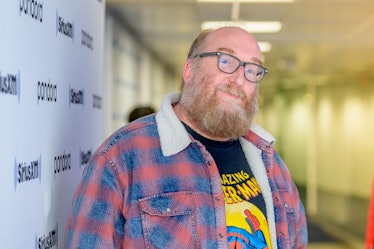 Brian Posehn in a black shirt yellow print and a blue-red-white check jacket