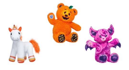 An image of three plush animals. One a bat cat, one a jack o lantern bear, one a candy corn unicorn.