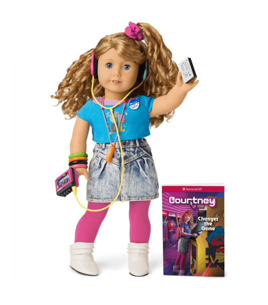 An American Girl named Courtney can be seen with a blue shirt, faded shorts, pink socks, white shoes...
