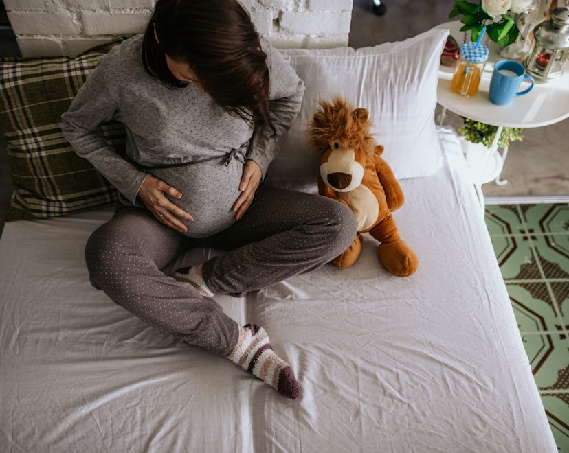 a pregnant woman holding belly on bed