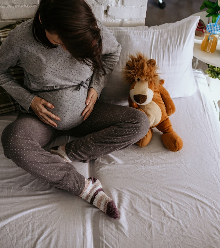 a pregnant woman holding belly on bed