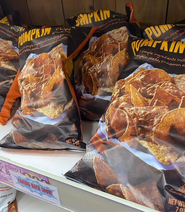 Bags of pumpkin tortilla chips haphazardly thrown on a shelf.