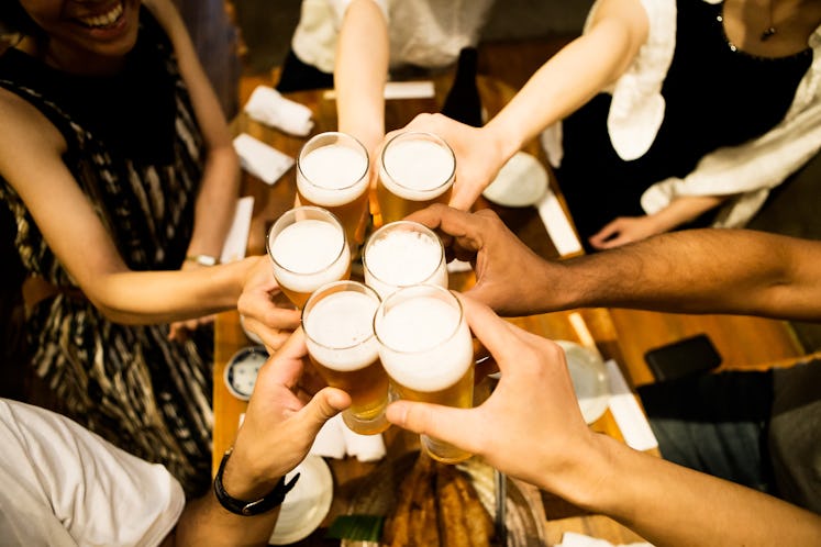 A group of people cheers with pints of beer.