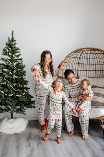 A family in festive long johns in front of a Charlie Brown Christmas tree. 