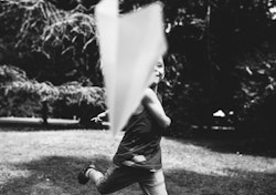 A little boy flies a paper airplane. Black and white photo.
