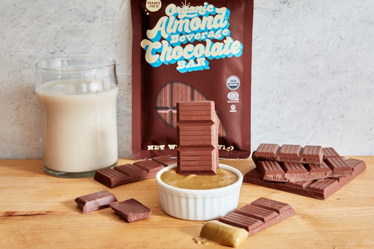 The Organic Almond Beverage Chocolate Bar from Trader Joe's sits on a wood table with almond milk an...