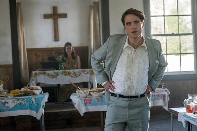 Actor Robert Pattinson wearing a white shirt and gray suit in a church for movie Devil All the Time,...