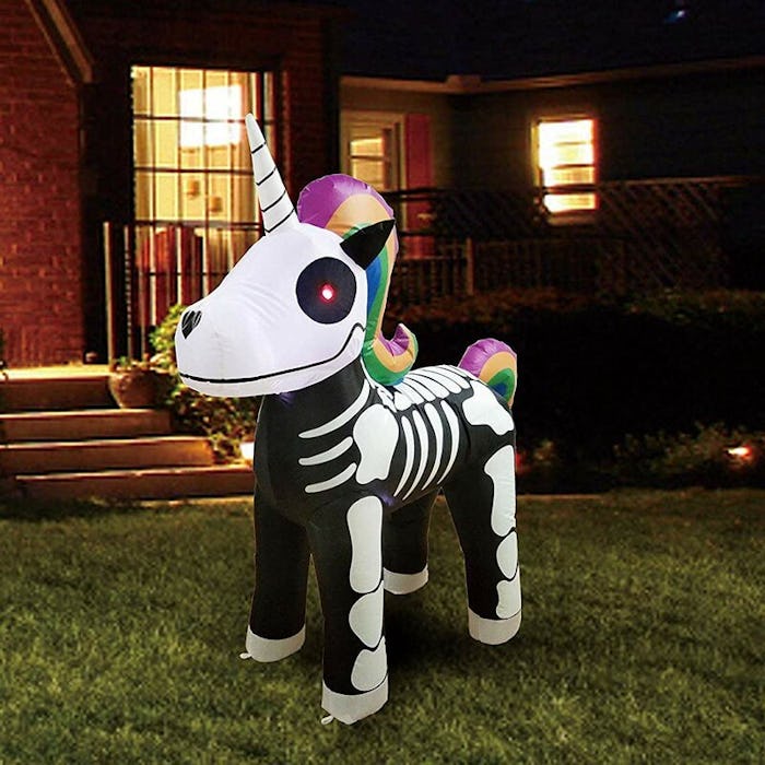 An image of an inflatable unicorn skeleton with a rainbow colored mane and tail in front of a house.