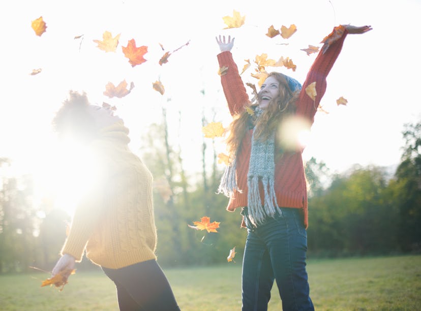 Young women playing in autumn leaves during the 2022 fall equinox.