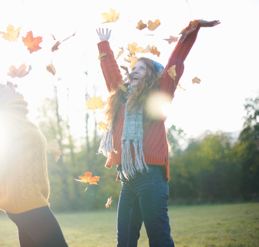 Young women playing in autumn leaves during the 2022 fall equinox.