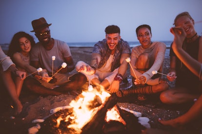 Young people roasting s'mores at beach bonfire