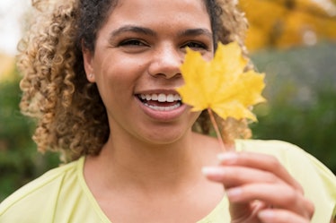 Young woman holding up fall leaf during the autumn equinox on Sept. 22, 2022.