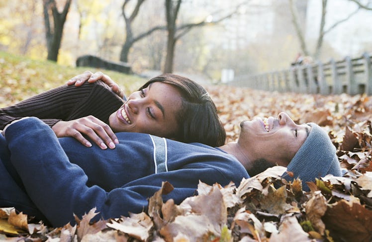 Young couple laying in fall leaves on the first day of fall 2022.