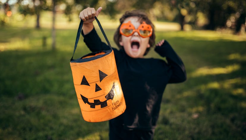 little boy dressed up for halloween with halloween pail