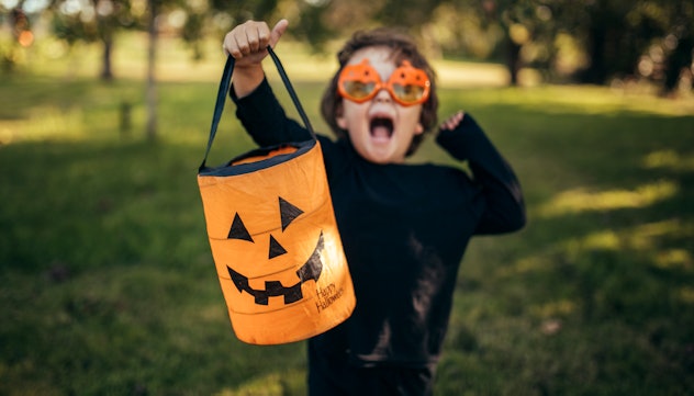 little boy dressed up for halloween with halloween pail