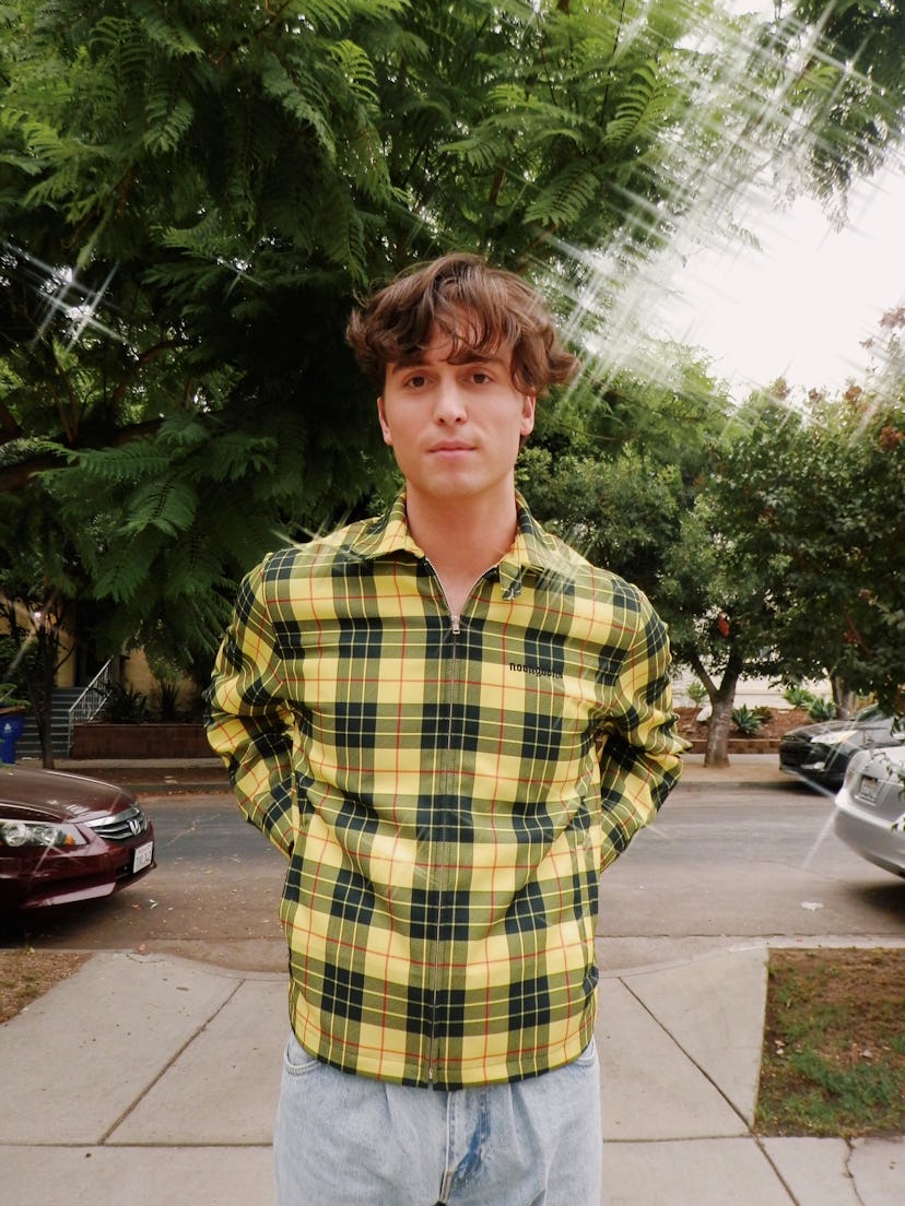 Benny Drama aka Benito Skinner wearing a black and yellow checkered shirt with light jeans 