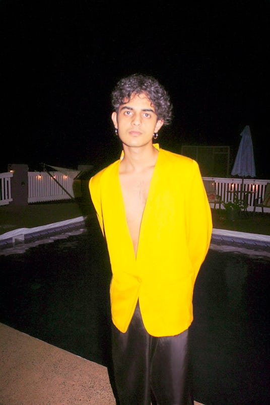 Curtis Waters wearing a yellow blazer with no shirt in front of his pool