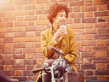 Young woman sipping coffee on bike