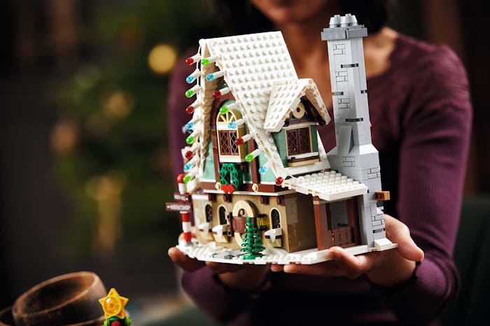 An image of a woman in an aubergine sweater holding a LEGO Elf Clubhouse.