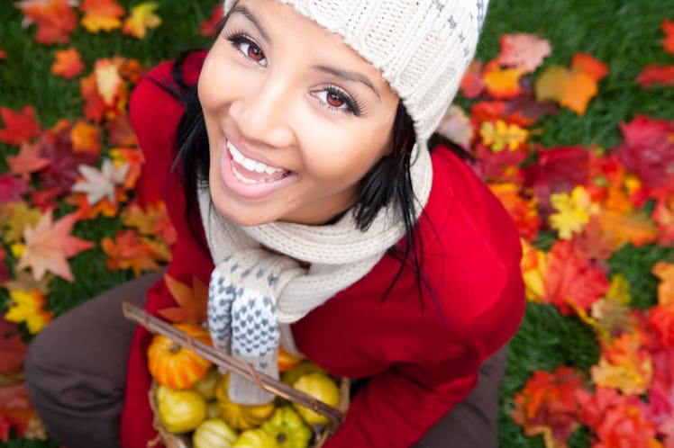 Young woman holding pumpkins in fall leaves