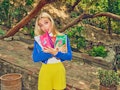 Emma Chamberlain poses in a colorful outfit while holding coffee bags from her new Chamberlain Coffe...