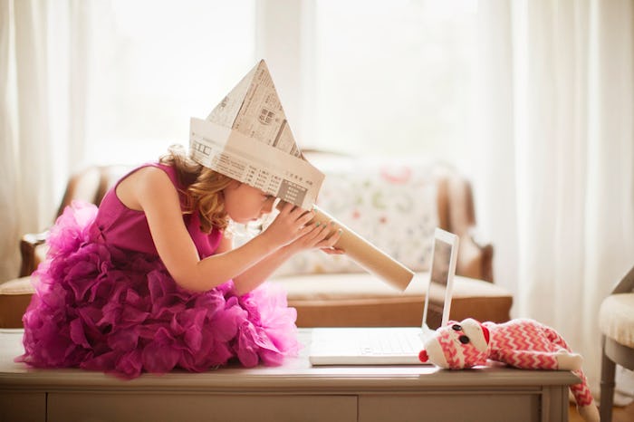 Child in newspaper hat looking through pretend telescope