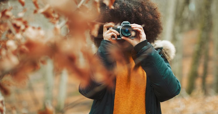 Young woman taking pictures of fall foliage for quotes on Instagram.