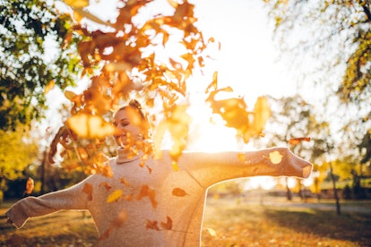 Young woman playing in fall leaves