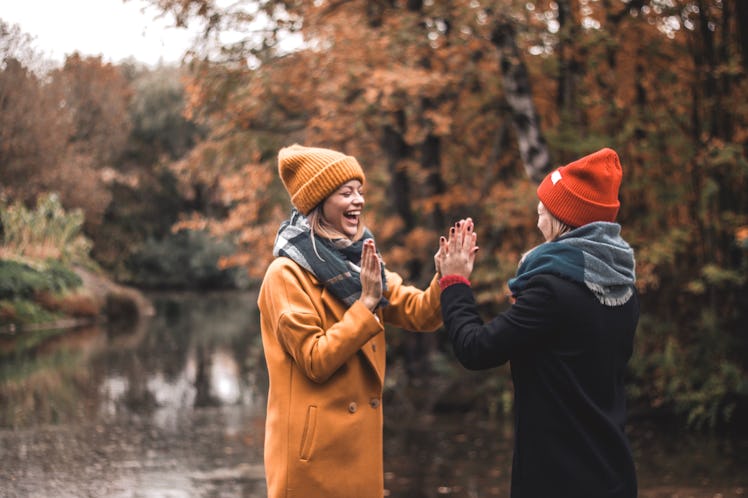 2 best friends playing hand games in fall