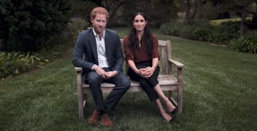 Prince Harry in a grey suit, and a white shirt, and Meghan Markle in a burgundy blouse and black pan...