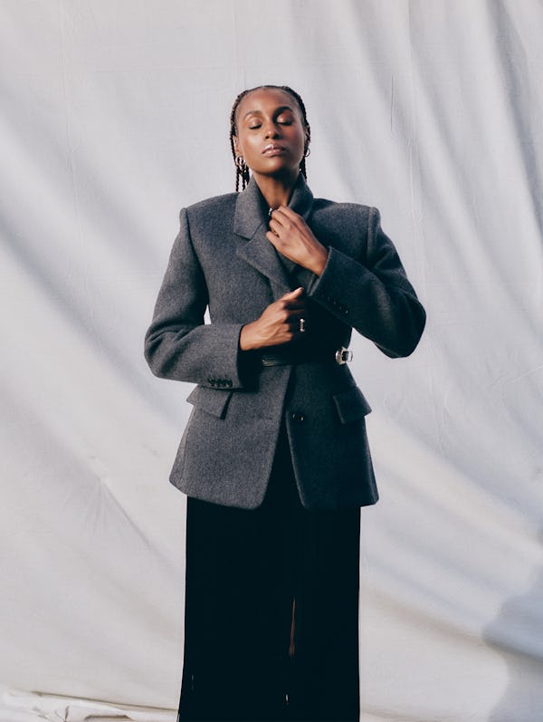 Issa Rae posing in a Prada jacket and skirt, an R13 belt and a Third Crown necklace and ring