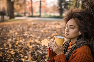 Young woman drinking coffee outside in the fall