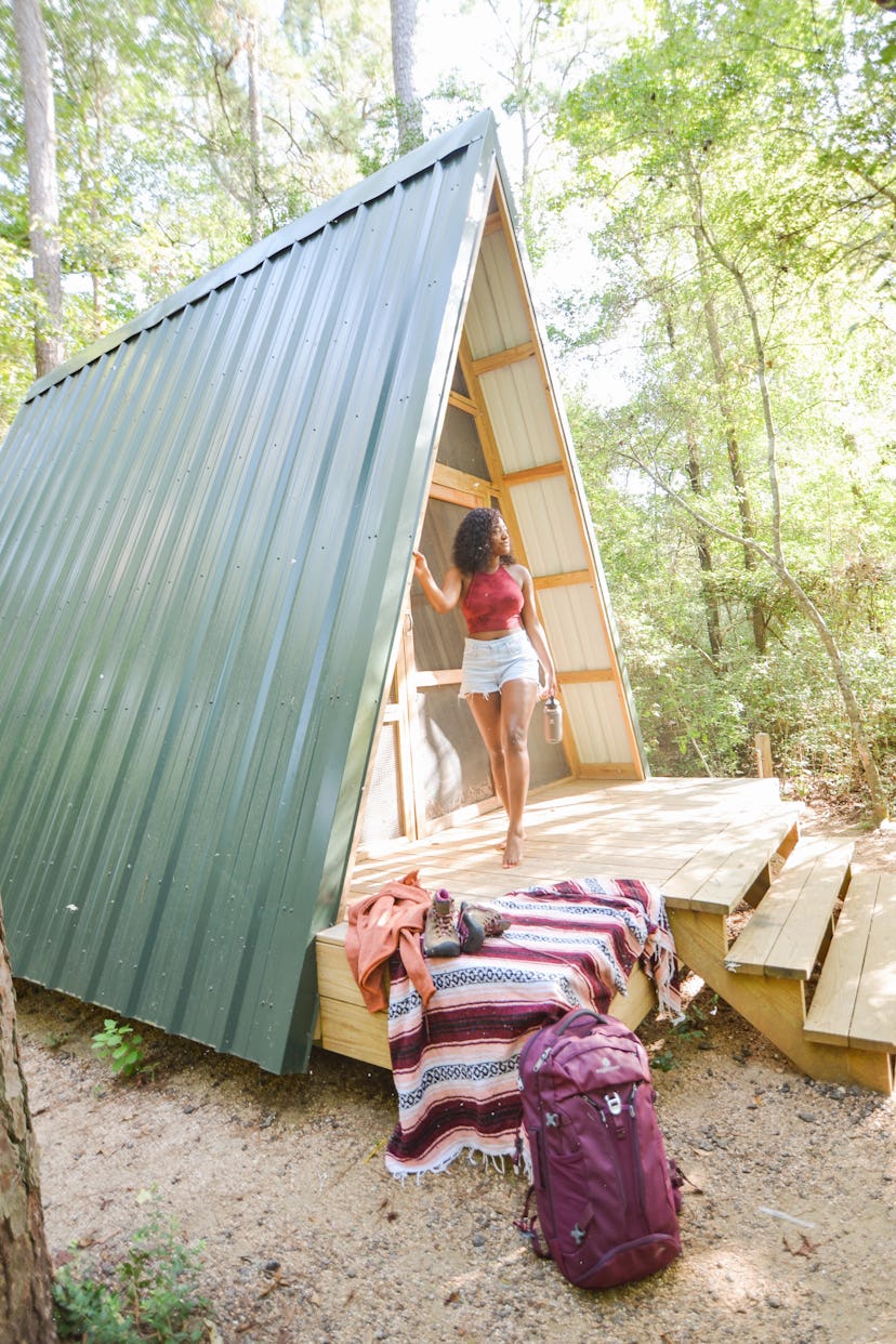 Ciara Johnson stepping out of a small cottage in the middle of the woods