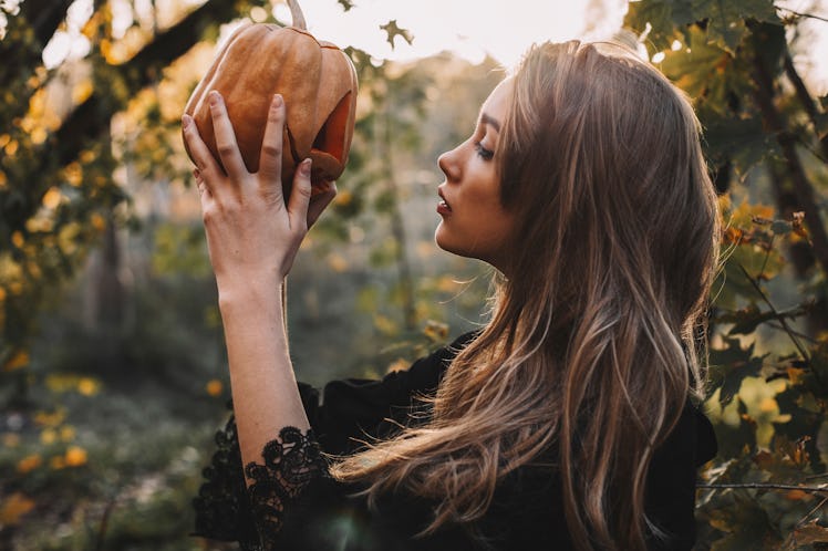 Young witch holding pumpkin