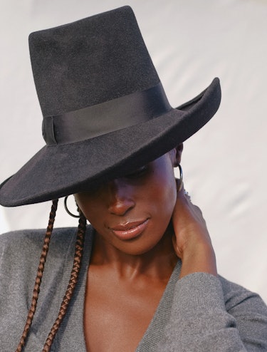 Issa Rae looking down in an Alexander Wang grey top and black Gucci hat