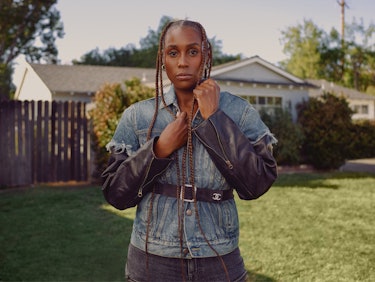 Issa Rae posing in a garden in pants and a jacket from R13 and a Chanel belt 